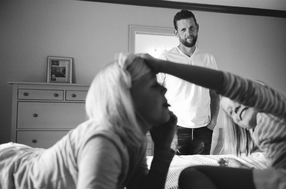 Father(Jeff) looking on proudly and wistfully at his two daughters (Kate and Alex) as they stick their tongues out at each other. ©William Bay Photographic Arts.